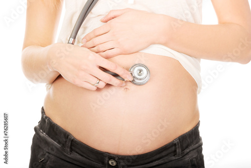 Pregnant woman with stethoscope listening her baby