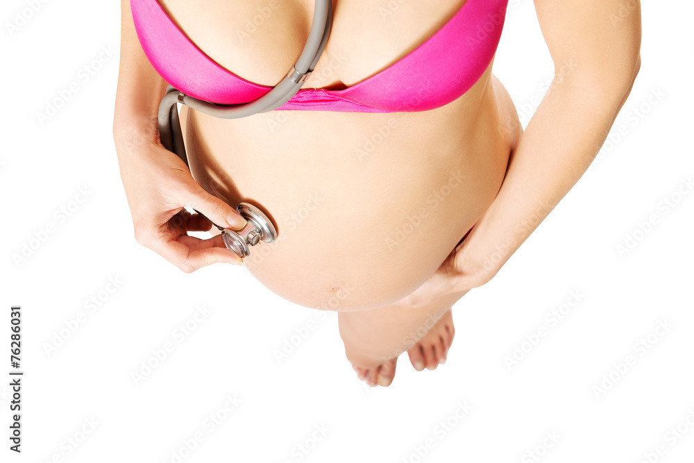 Pregnant woman holding stethoscope on belly