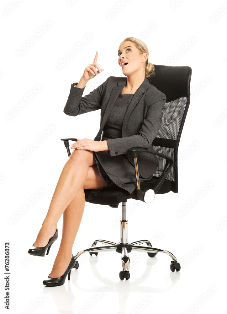 Businesswoman sitting on a chair and showing empty space Businesswoman sitting on a chair and showing empty space