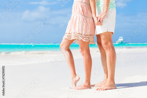 legs of young hugging couple on tropical turquoise beach