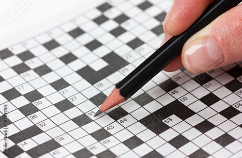 Fotografía woman hand holding a pencil and solves crossword puzzle