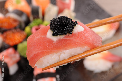 Tuna sushi with caviar held by chopsticks