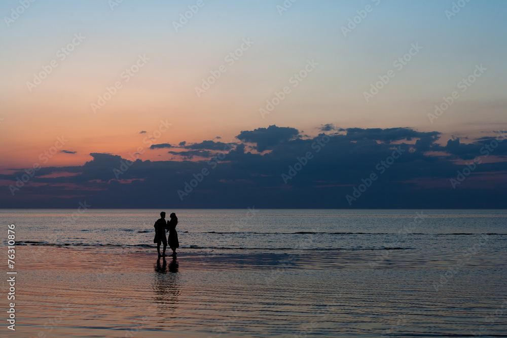 Silhouettes of young people on the beach at sunset