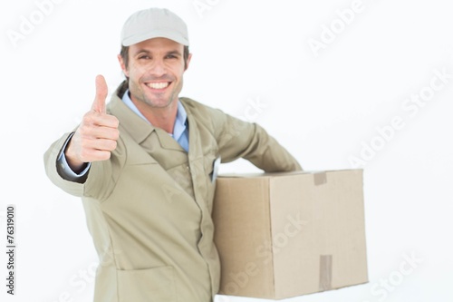 Happy delivery man gesturing thumbs up while carrying box