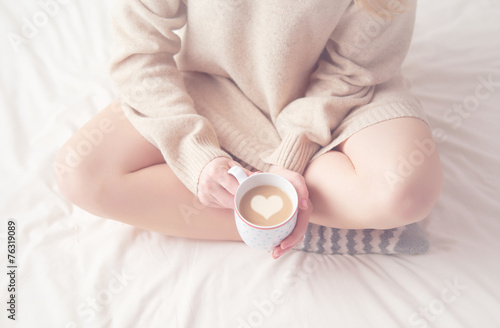 legs of girl warm woolen socks and cup of coffee