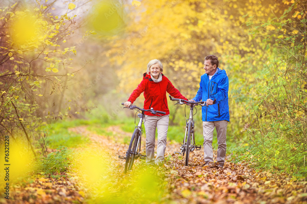 Active seniors walking with bike Active seniors walking with bike