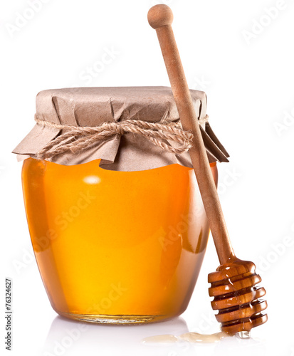 Photographie Glass can full of honey and wooden stick on a white background.