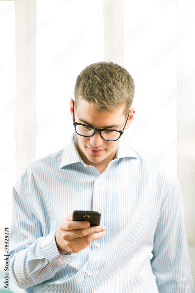 Handsome young businessman using mobile phone over blurred backg Handsome young businessman using mobile phone over blurred backg