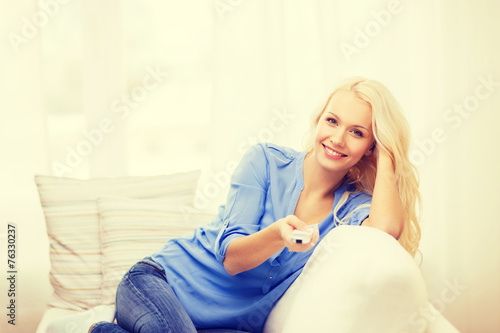 smiling young girl with tv remote control at home