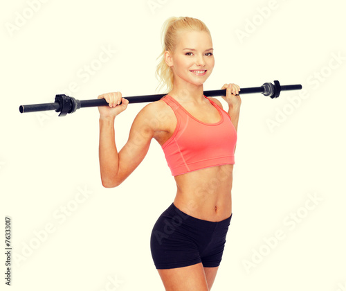 smiling sporty woman exercising with barbell