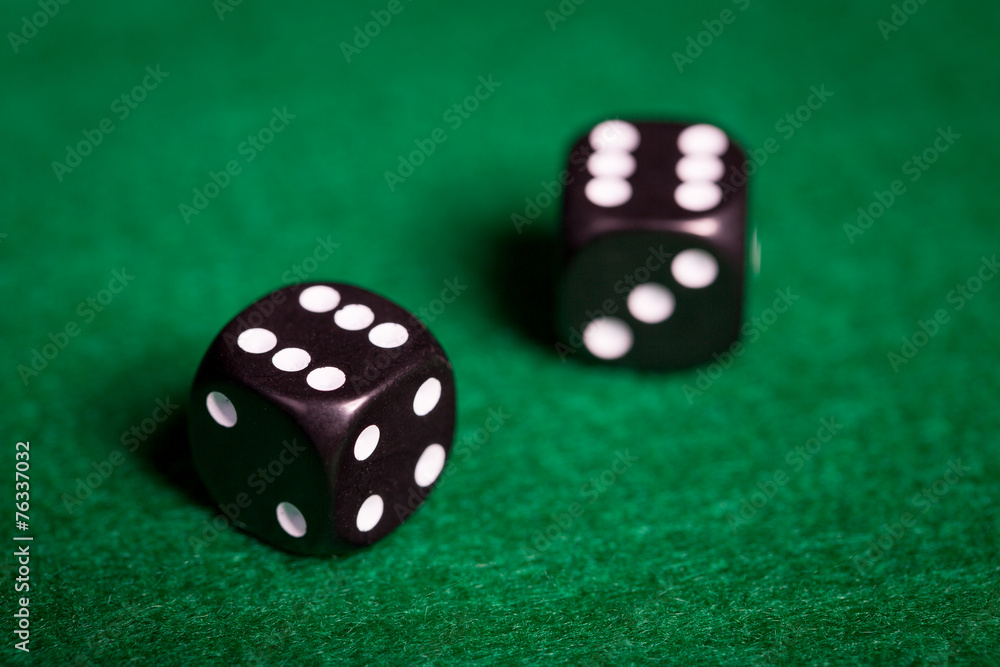 close up of black dice on green casino table close up of black dice on green casino table