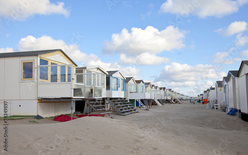 Beach houses on beach in a row with blue sky