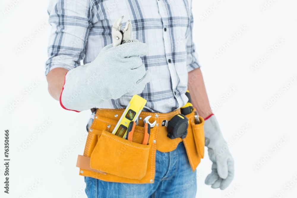 Technician with tool belt around waist holding pliers Technician with tool belt around waist holding pliers