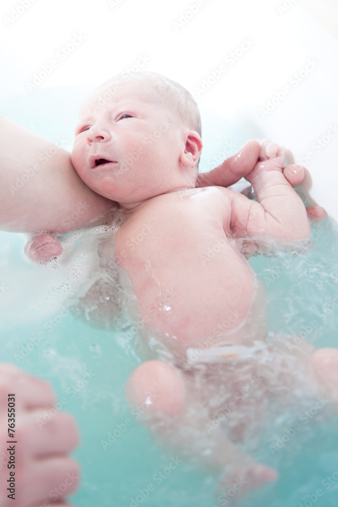 Little newborn baby boy first bathes in blue bath Little newborn baby boy first bathes in blue bath
