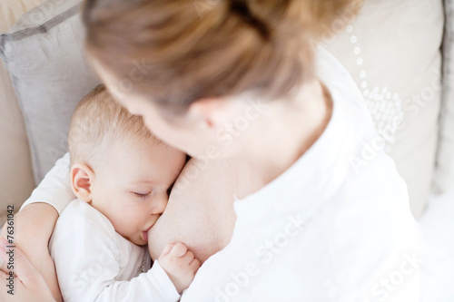 Young mother breastfeeding the newborm baby - indoors