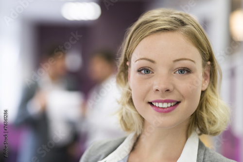 Pretty Businesswoman posing while colleagues talking together in