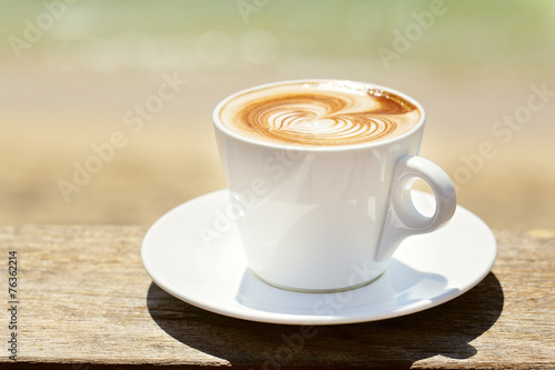 Cappuchino or latte coffe in a white cup with heart shaped foam