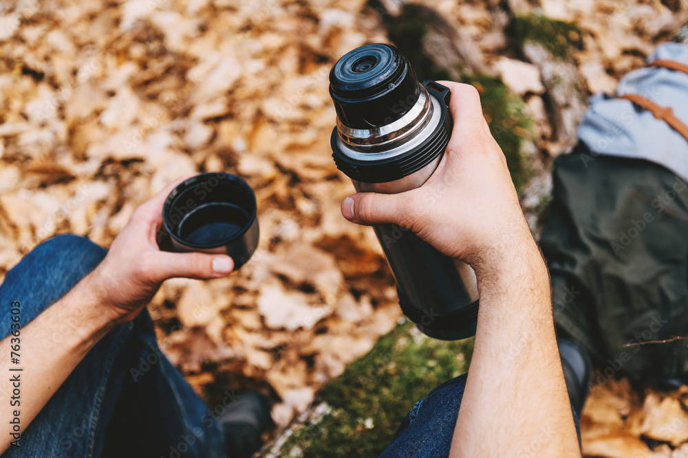 Traveler man holding thermos in autumn forest Traveler man holding thermos in autumn forest