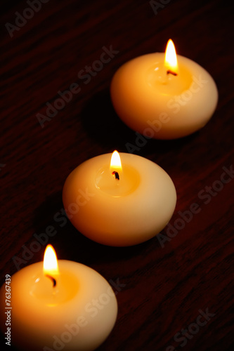 Three candles on a dark wooden table.