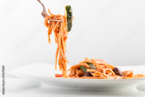Spaghetti with tomato sauce and courgette on a fork
