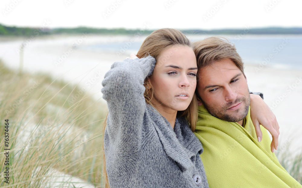 Attractive lovely woman and man sit in the sand dune of a beach Attractive lovely woman and man sit in the sand dune of a beach