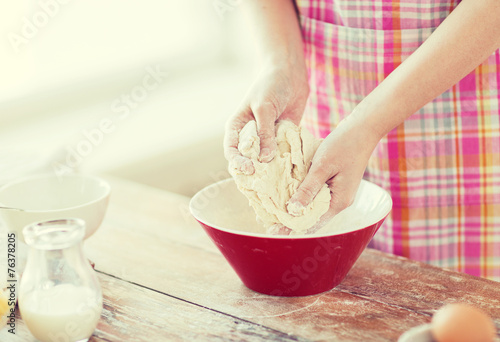 close up of female hands kneading dough at home