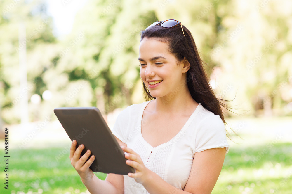 smiling young girl with tablet pc sitting on grass smiling young girl with tablet pc sitting on grass
