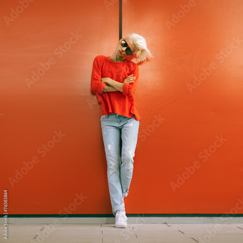 Stylish blonde stand near red wall on city street. Urban Casual photo