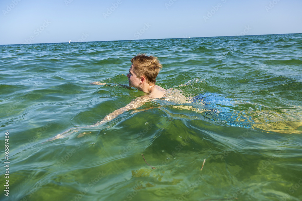 handsome teen has fun swimming in the ocean