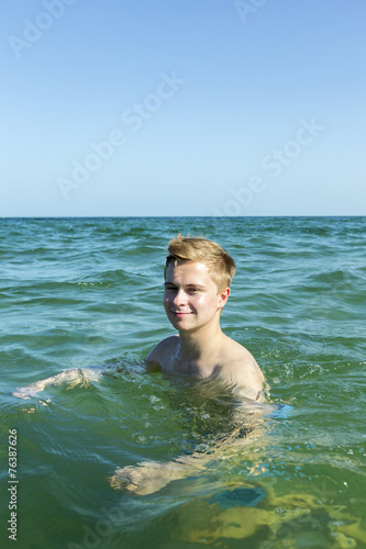 handsome teen has fun swimming in the ocean © travelview