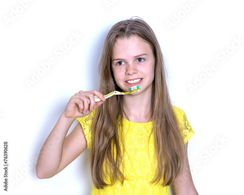 Young girl in a yellow dress brushing her teeth