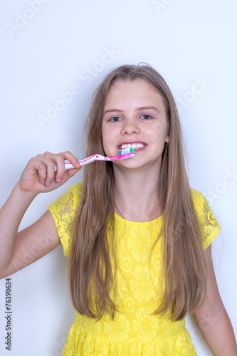 Young girl brushing her teeth. On gray background