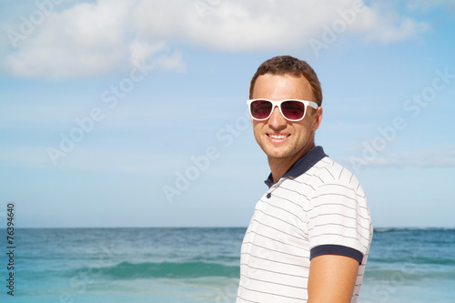 Man standing with white sunglasses on summer sea coast