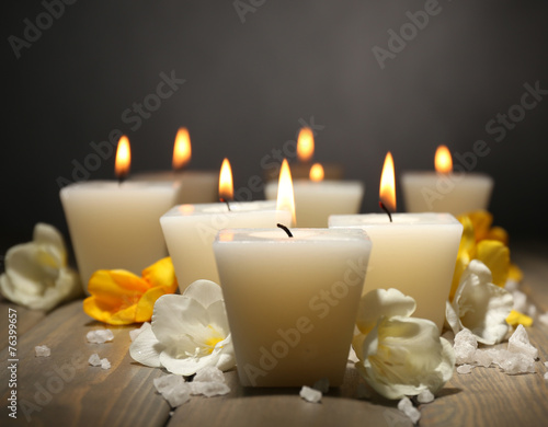 Beautiful candles with flowers on wooden background