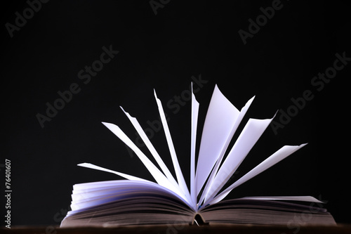Open book on wooden surface and dark background