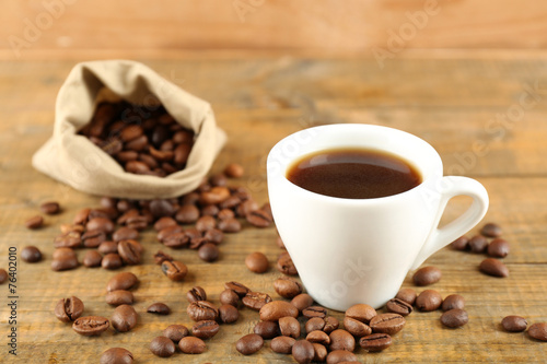 Cup of coffee with beans on rustic wooden background