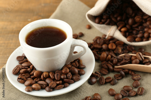 Cup of coffee with beans on rustic wooden background