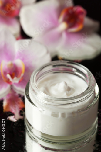 Fototapeta Naklejka Na Ścianę i Meble -  Face cream with orchid flowers on dark background