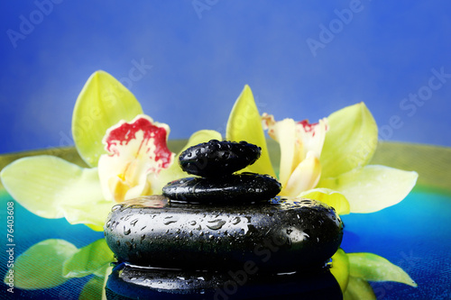 Spa stones with steam and beautiful blooming orchid in water