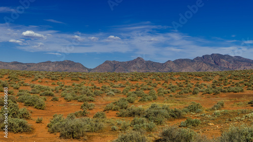 Cloudy desert landscape wtith mountain ranges in background