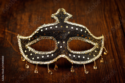 Glittering carnival mask on wooden table
