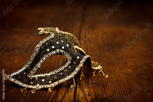 Black and golden mask on rustic table