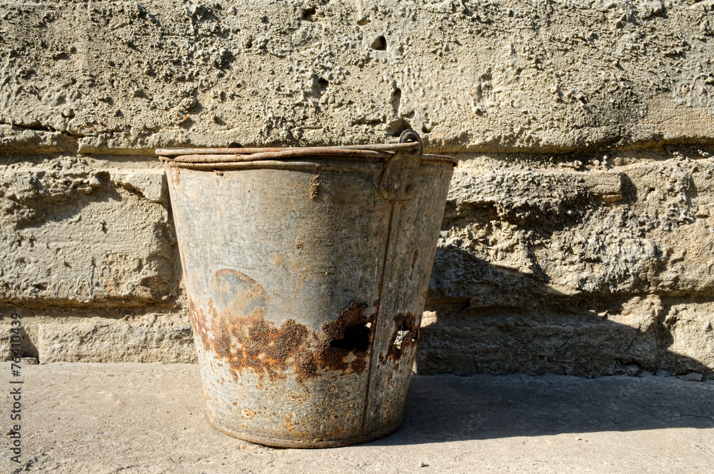 old bucket on background of a cement wall