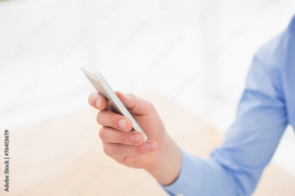 Businessman text messaging with his smartphone Businessman text messaging with his smartphone
