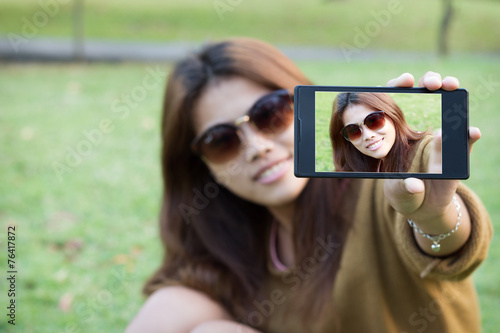 pretty women wear eyeglass smile use smart phone mobile take sel