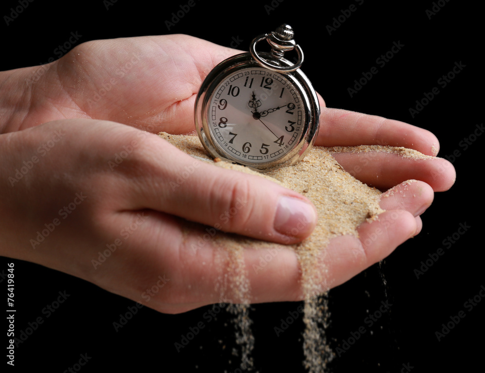 Silver pocket clock in hands and sand flowing away Silver pocket clock in hands and sand flowing away