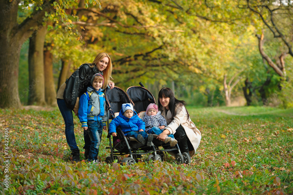mothers with children twins on a walk in the autumn park mothers with children twins on a walk in the autumn park