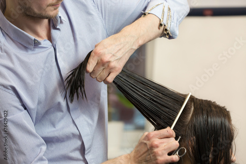 Hairdresser making a haircut for a brunette girl