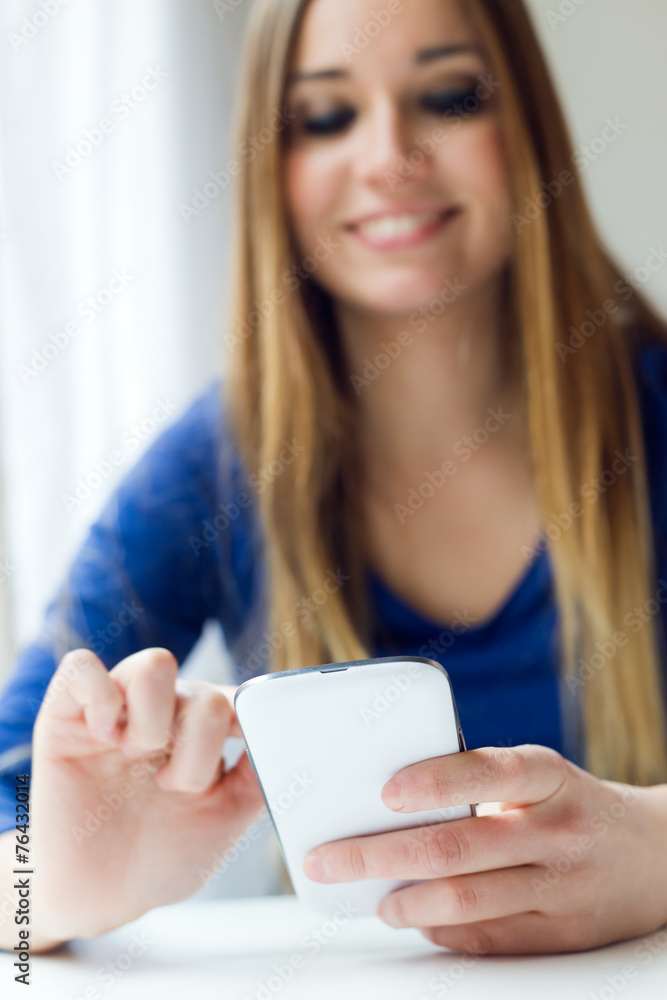 Young beautiful woman using her mobile phone at home. Young beautiful woman using her mobile phone at home.
