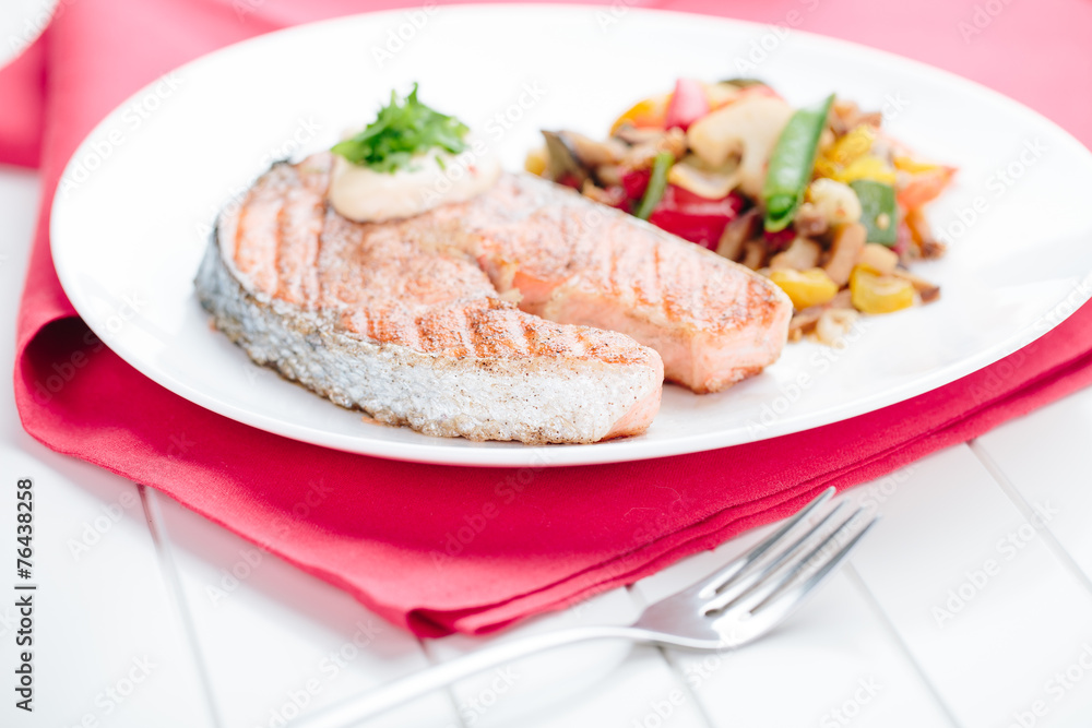 Grilled Salmon with Fresh vegetables on red background